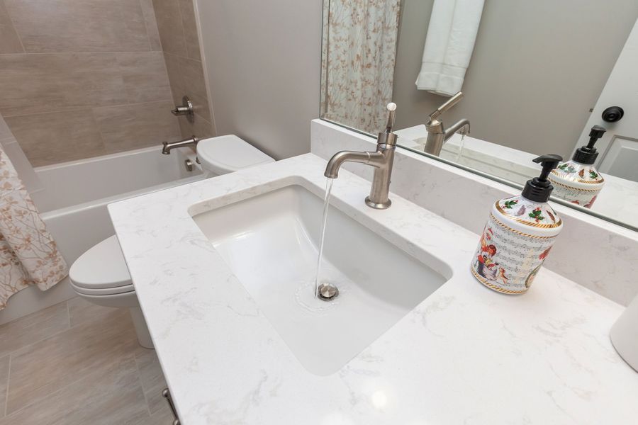 A bathroom with a sink , toilet , tub and mirror.
