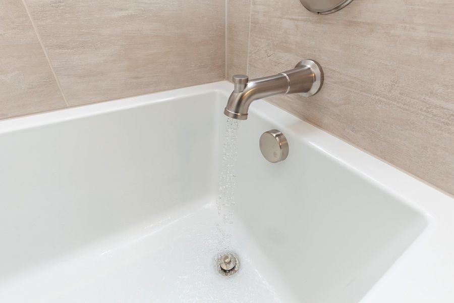 A white bathtub with water running from the faucet.