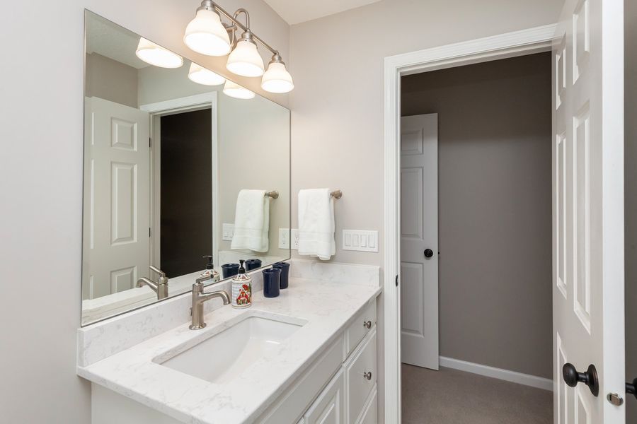 A bathroom with a sink , mirror and towel rack.