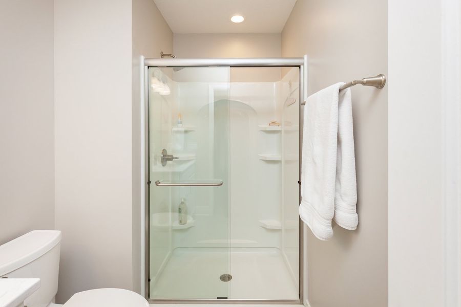A bathroom with a toilet , shower , and towel rack.
