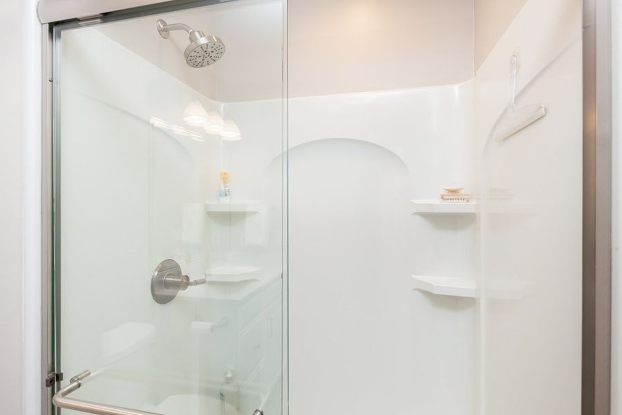 A bathroom with a sliding glass shower door and a shower head.