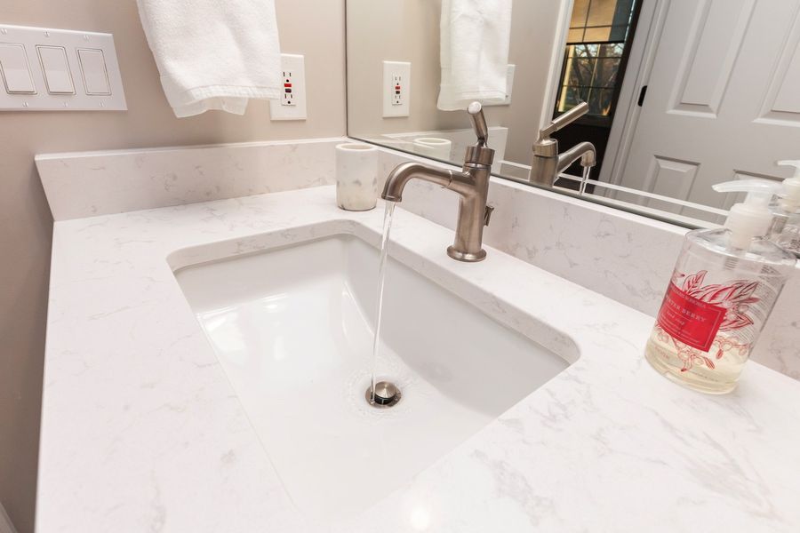 A bathroom sink with a soap dispenser next to it and a mirror.