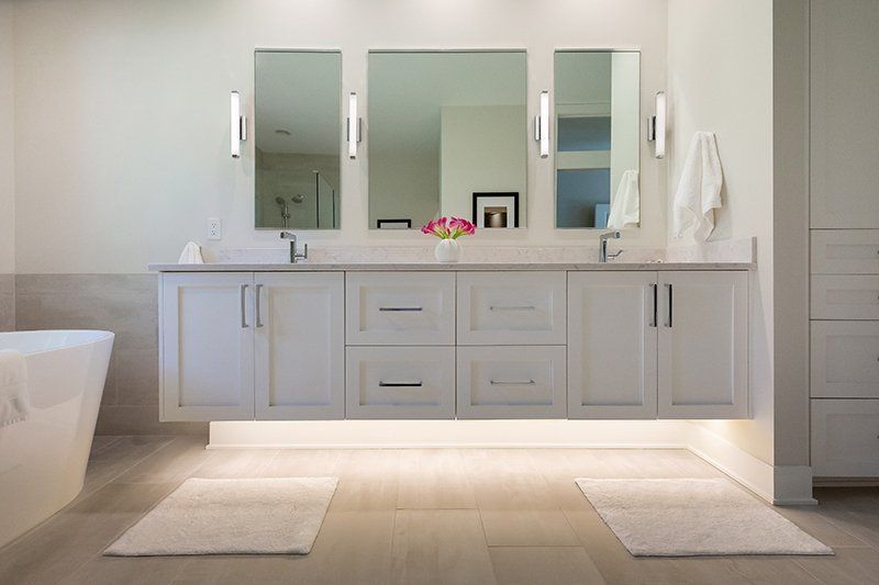 A bathroom with two sinks , two mirrors and a bathtub.