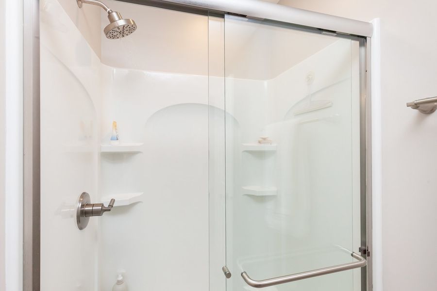 A bathroom with a sliding glass shower door and a shower head.
