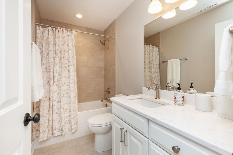 A bathroom with a toilet , sink , shower and mirror.