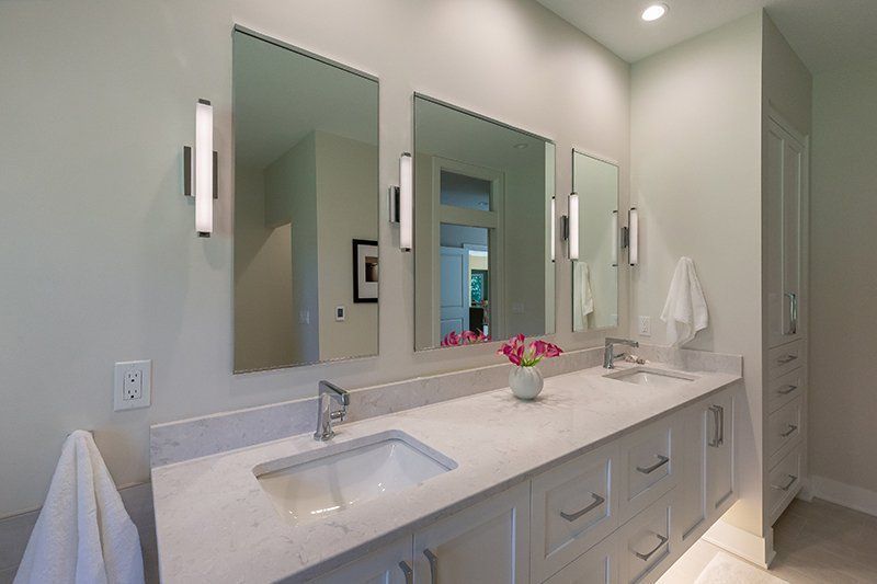 A bathroom with two sinks and three mirrors.