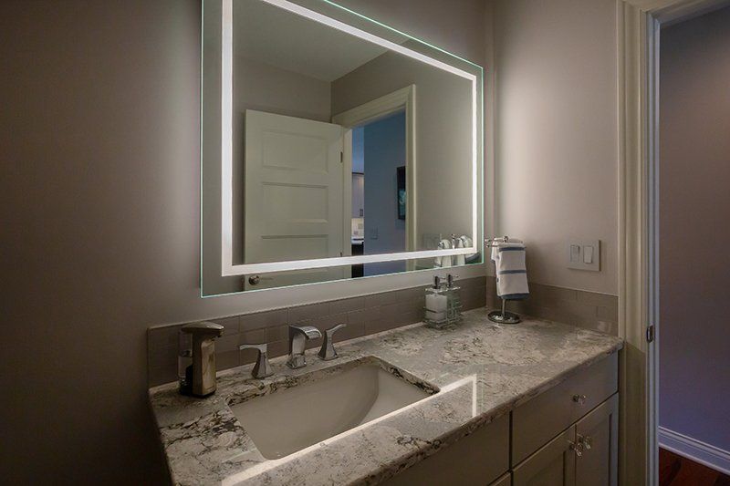 A bathroom with a sink and a mirror with lights on it.