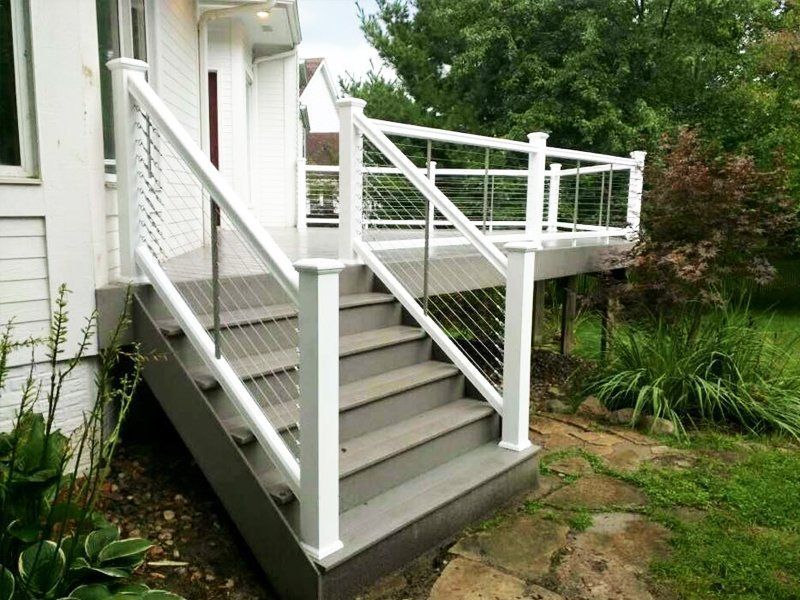A white house with a deck and stairs leading up to it.