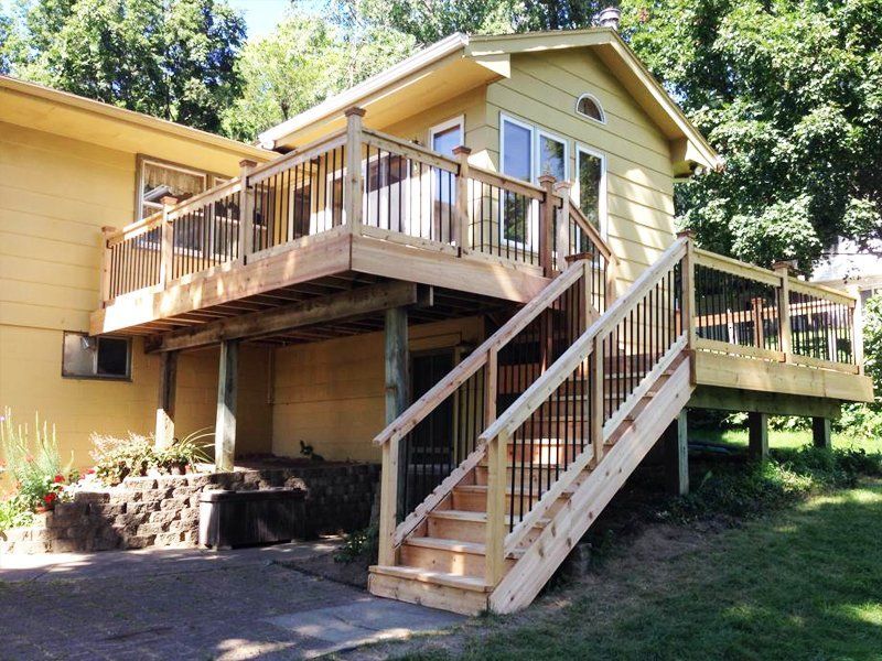 A yellow house with a wooden deck and stairs