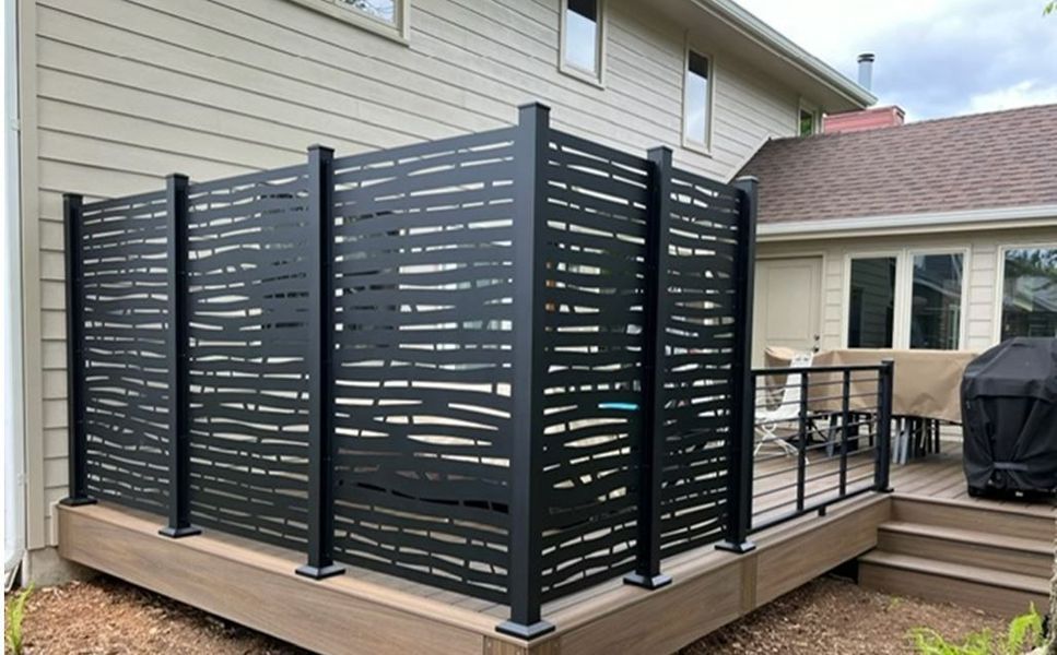 A deck with a fence around it and a house in the background.