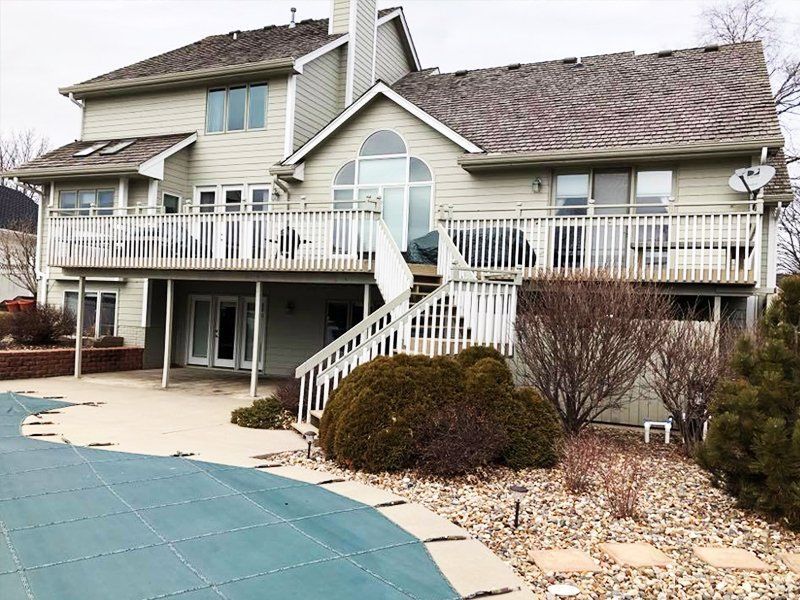 A large house with a large deck and a swimming pool in front of it.