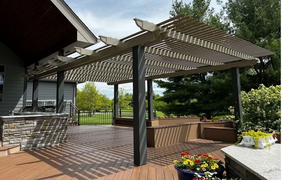 A deck with a pergola and flowers on it
