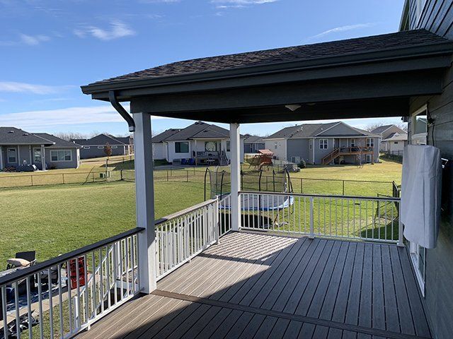 A large deck with a white railing and a roof over it.