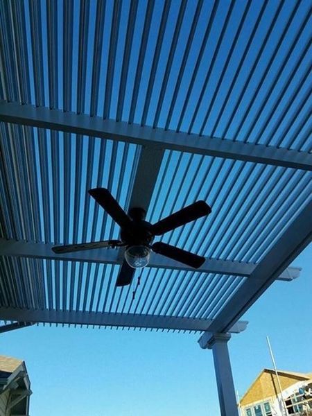 A ceiling fan is hanging from the ceiling of a pergola.
