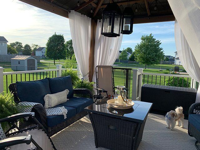 A patio with a couch , table , chairs and a dog.