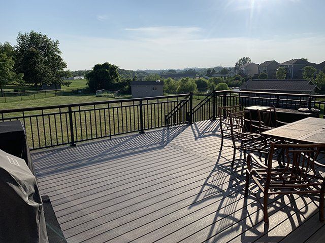 A large deck with a table and chairs and a grill.