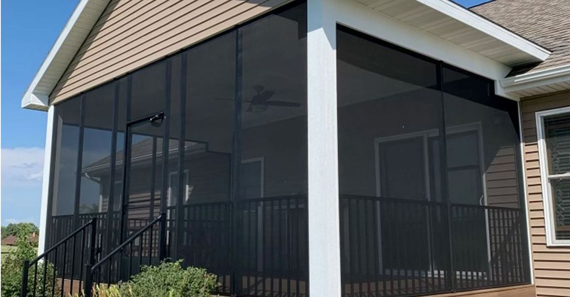 A screened in porch with a railing and stairs on the side of a house.