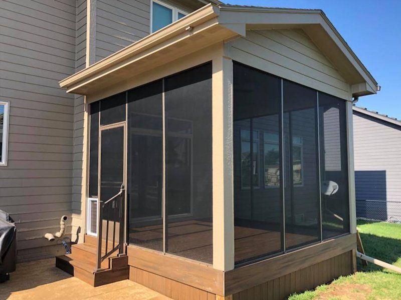 A screened in porch on the side of a house.