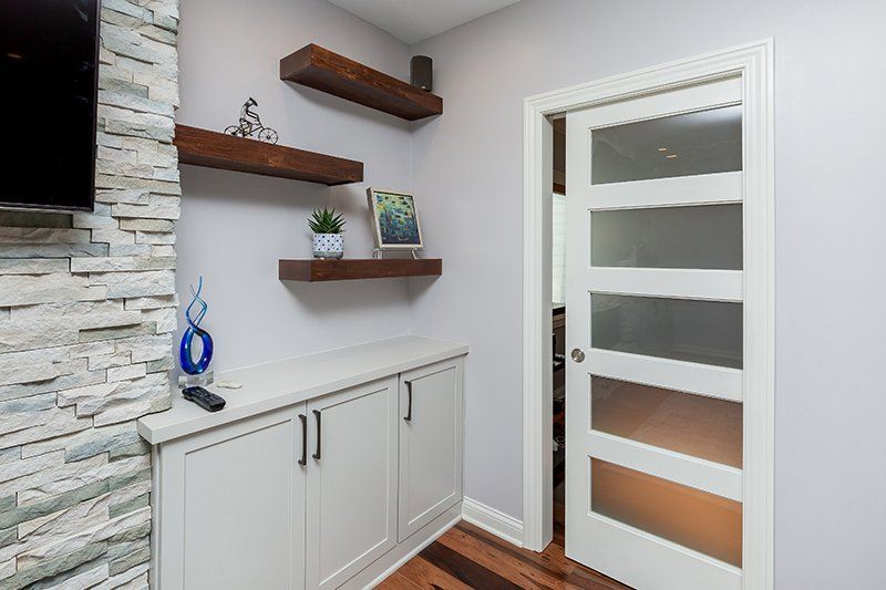 A hallway in a house with a door and shelves.