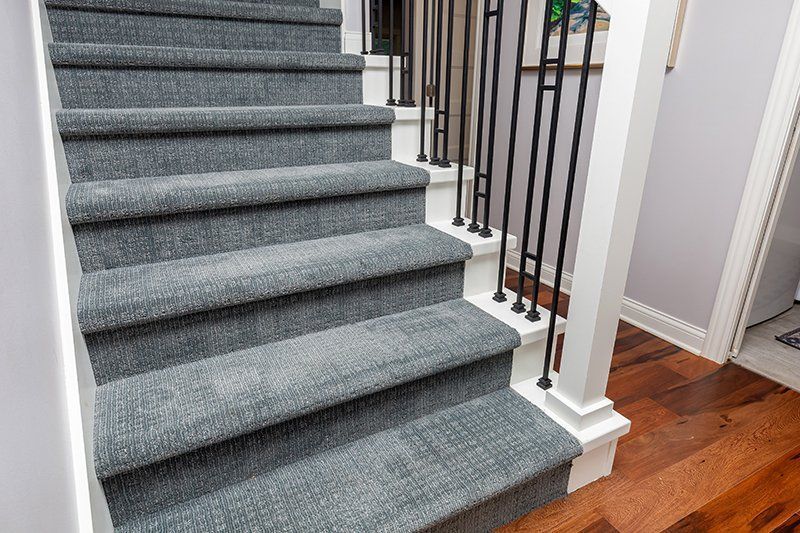A set of stairs with carpeted steps and a metal railing.