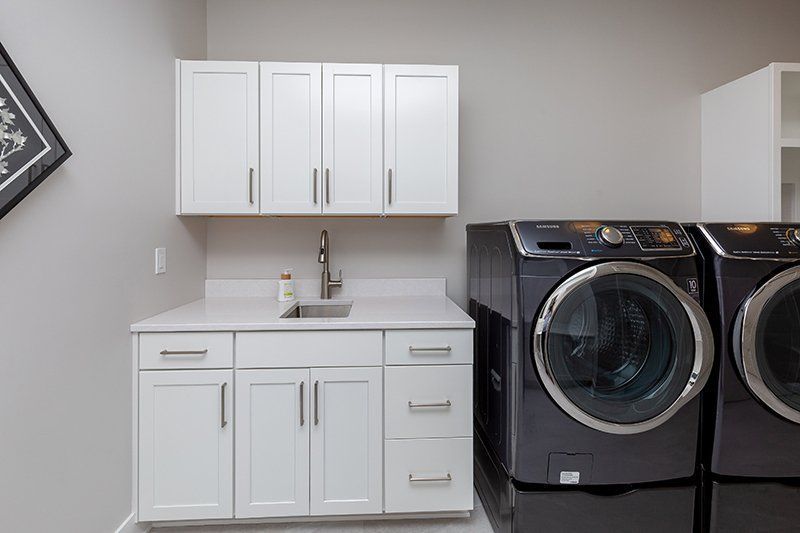 A laundry room with two washing machines and a sink