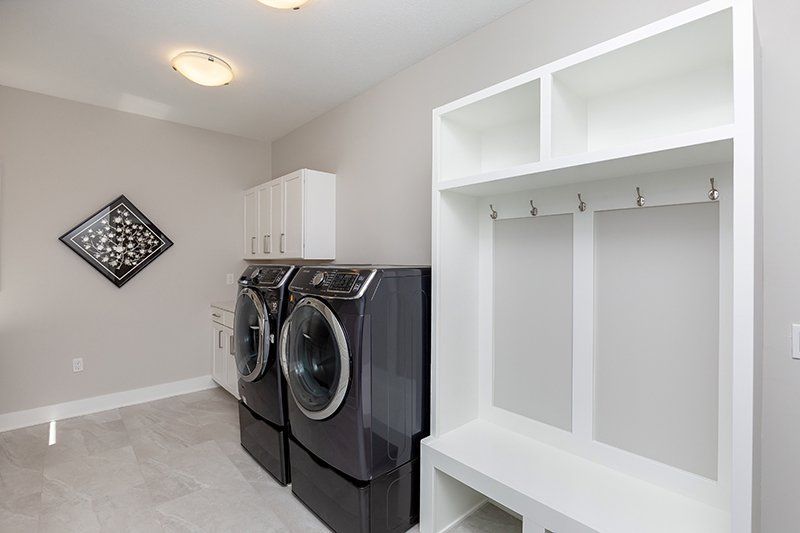 A laundry room with a washer and dryer and a bench.