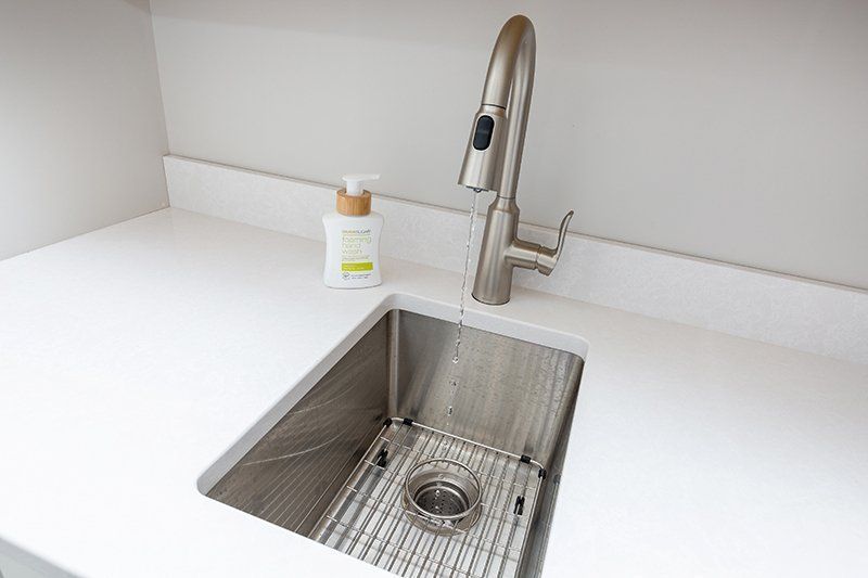 A kitchen sink with a faucet and a soap dispenser on the counter.