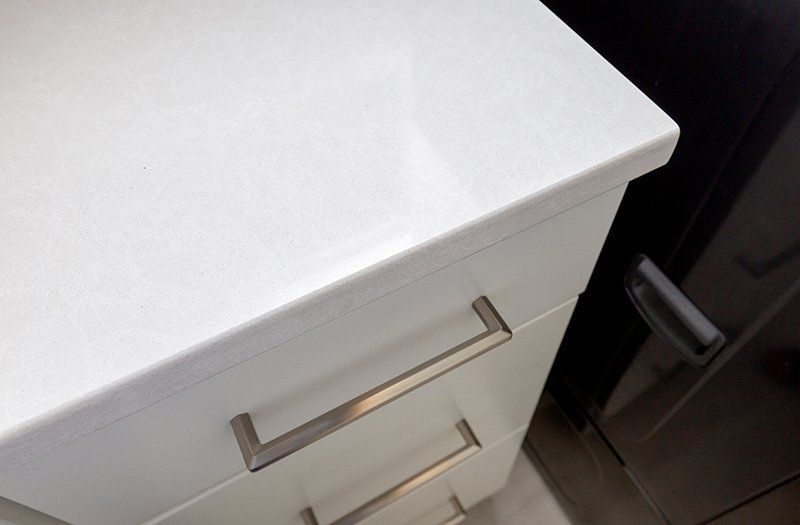 A close up of a white cabinet with stainless steel handles
