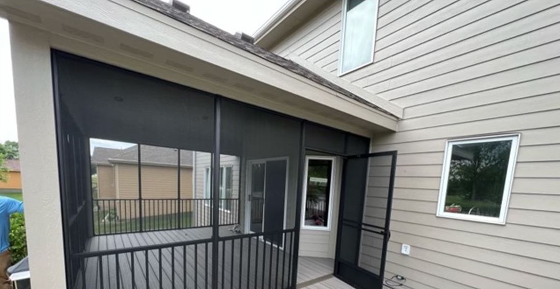 A screened in porch is attached to the side of a house.
