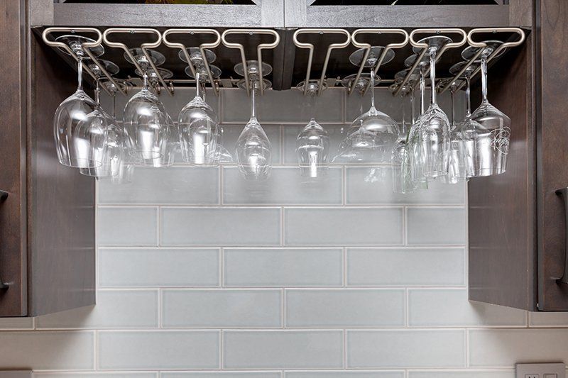 A wine glass rack with wine glasses hanging from it in a kitchen.