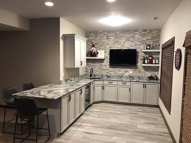 A kitchen with white cabinets and a flat screen tv on the wall.