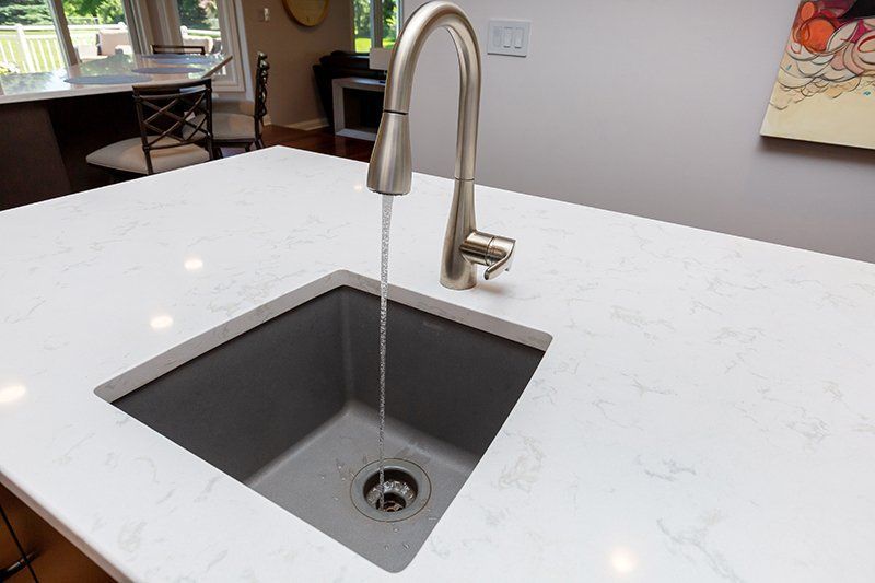 A kitchen sink with water running from the faucet.