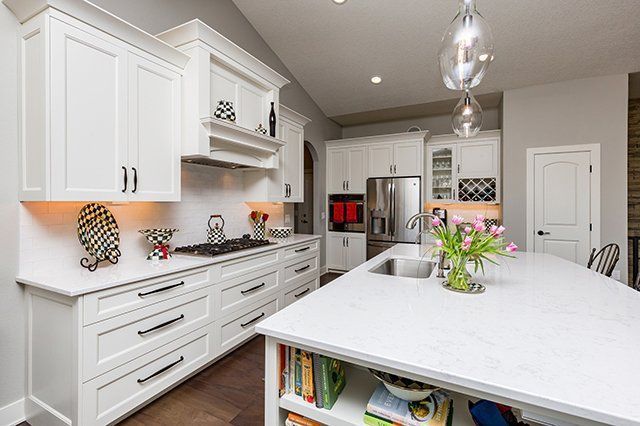 A kitchen with white cabinets and a large island in the middle.