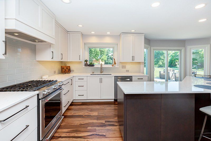 A kitchen with white cabinets , stainless steel appliances , and a large island.
