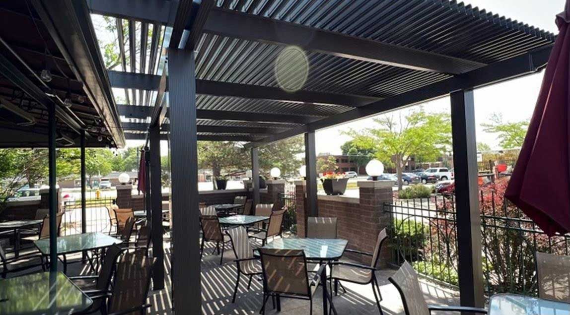A patio with tables and chairs under a pergola