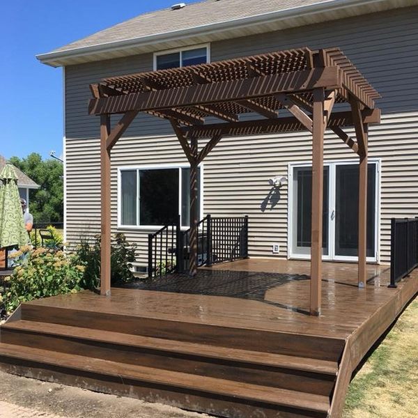 A wooden deck with stairs and a pergola in front of a house