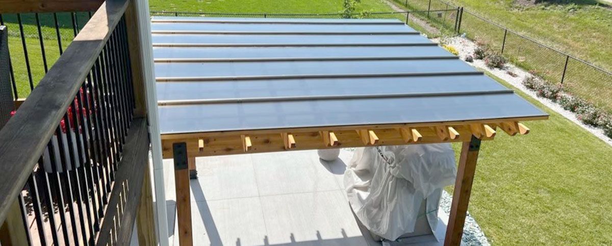 A pergola is sitting on top of a patio next to a railing.