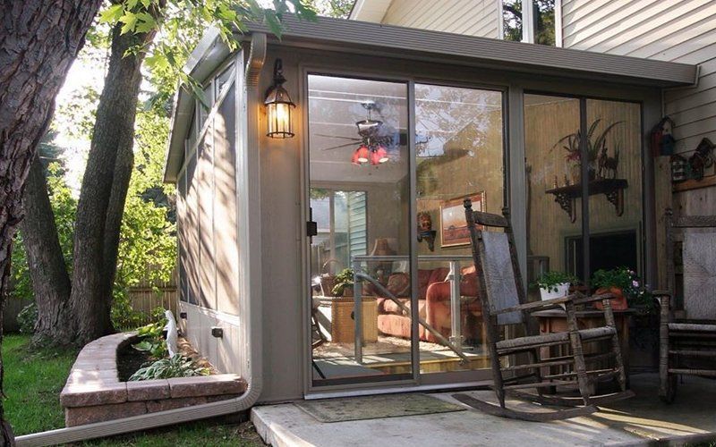A sliding glass door leads to a living room with rocking chairs.