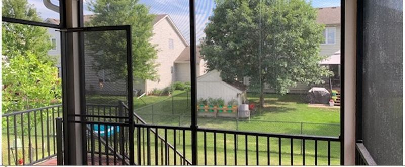 A screened in porch with a view of a backyard.