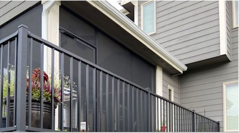 A balcony with a black railing on the side of a house.