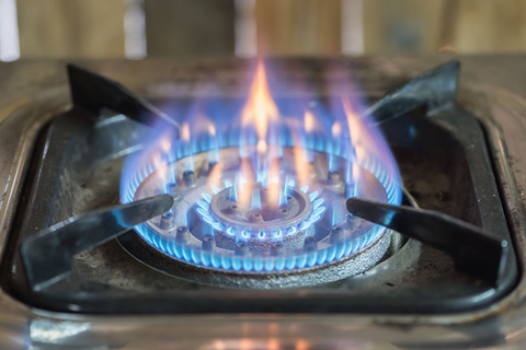Gas stove burner with blue and orange flames.