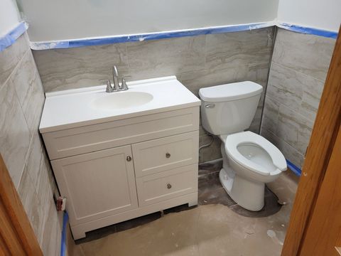 Small bathroom with white vanity sink, toilet, and gray tiled walls.