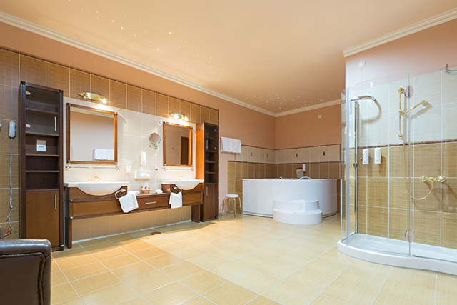 Spacious beige bathroom with double sinks, tub, shower, and wooden cabinets.