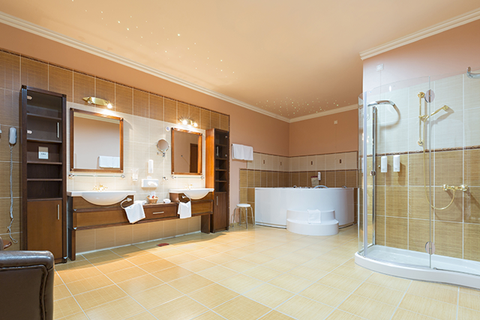 Spacious beige bathroom with double sinks, tub, shower, and wooden cabinets.