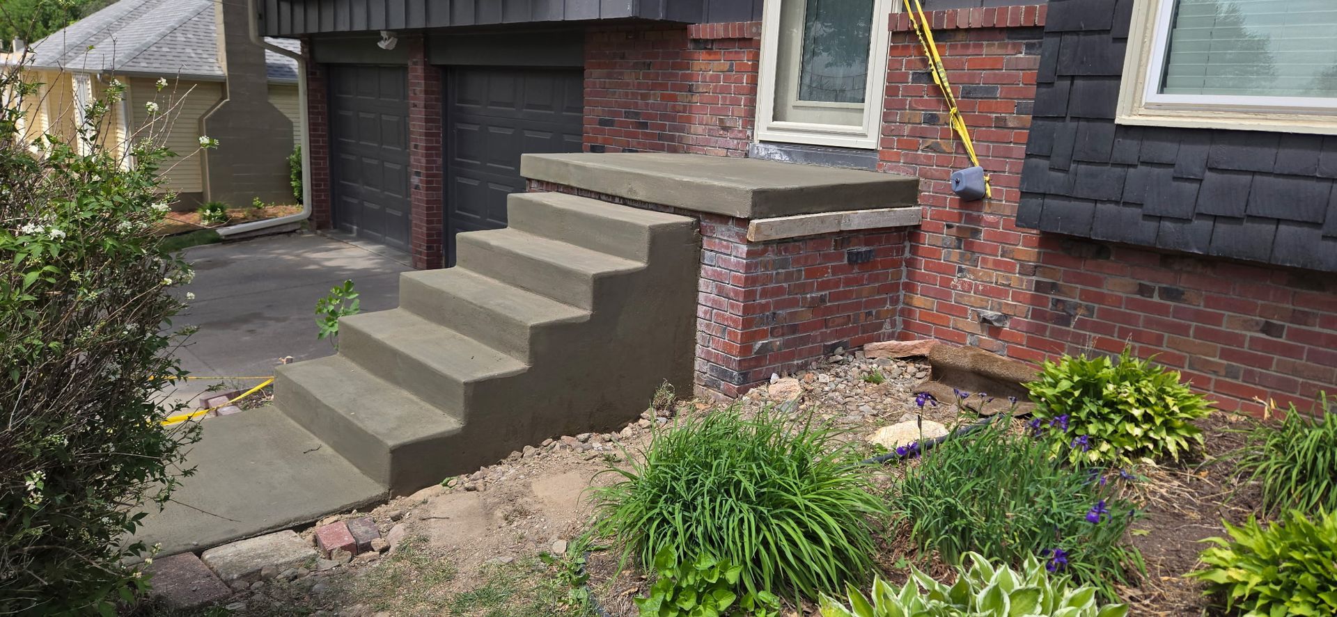 A concrete staircase is being built in front of a brick house.