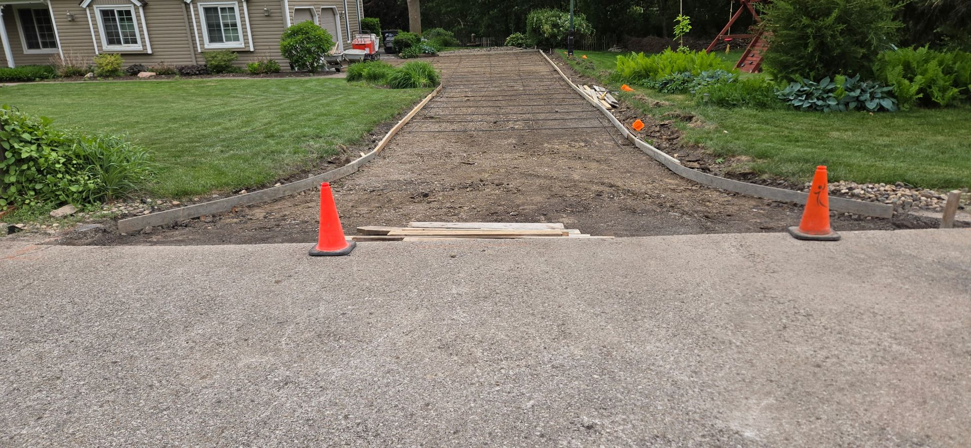 Two orange cones are sitting on the side of a dirt road.