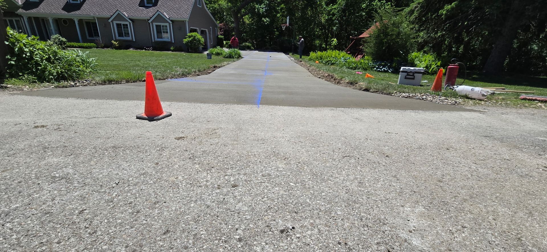 An orange traffic cone is sitting on the side of a road.