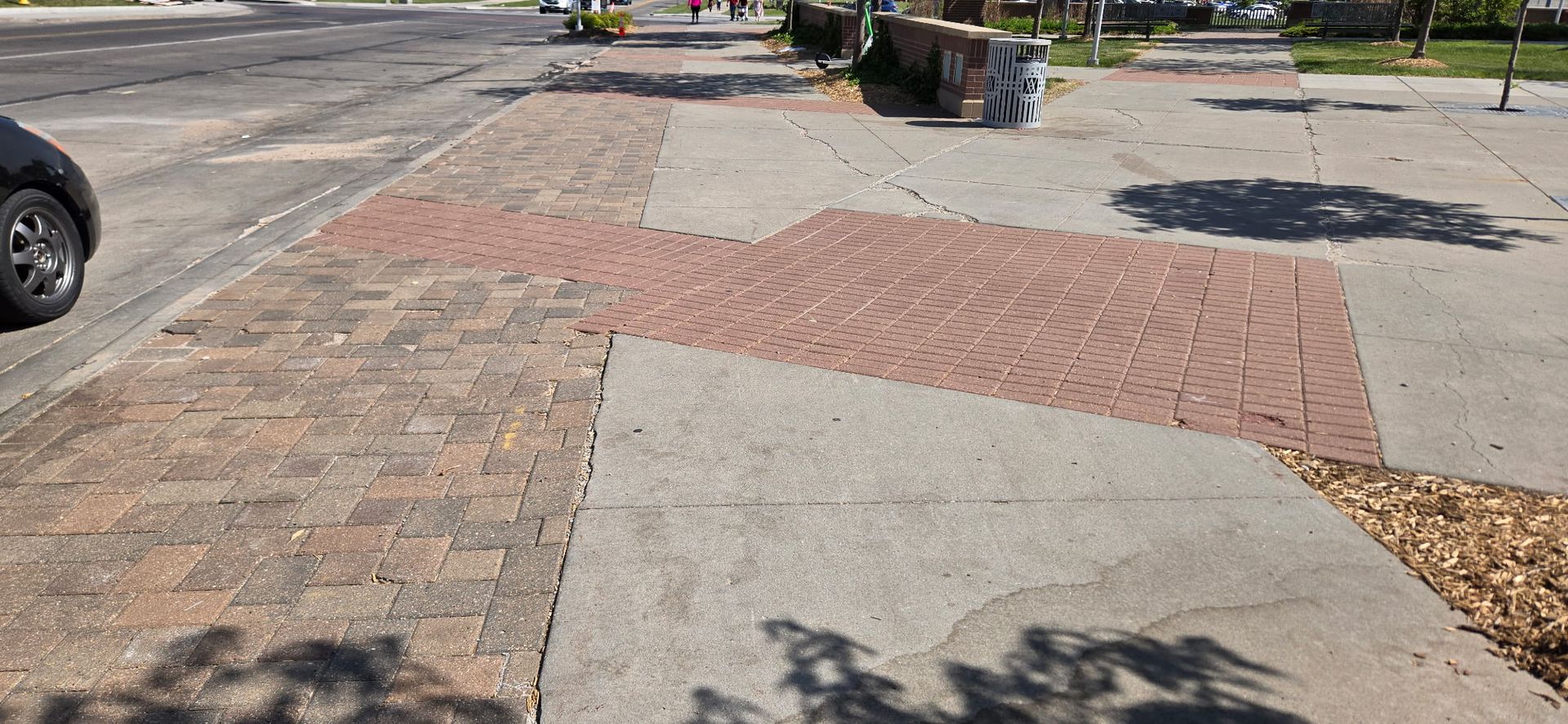 A car is parked on the side of the road next to a brick sidewalk.