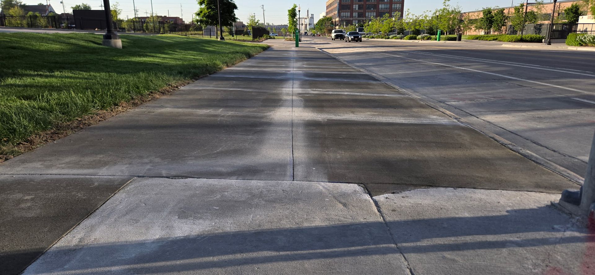 A person is walking down a sidewalk next to a street.