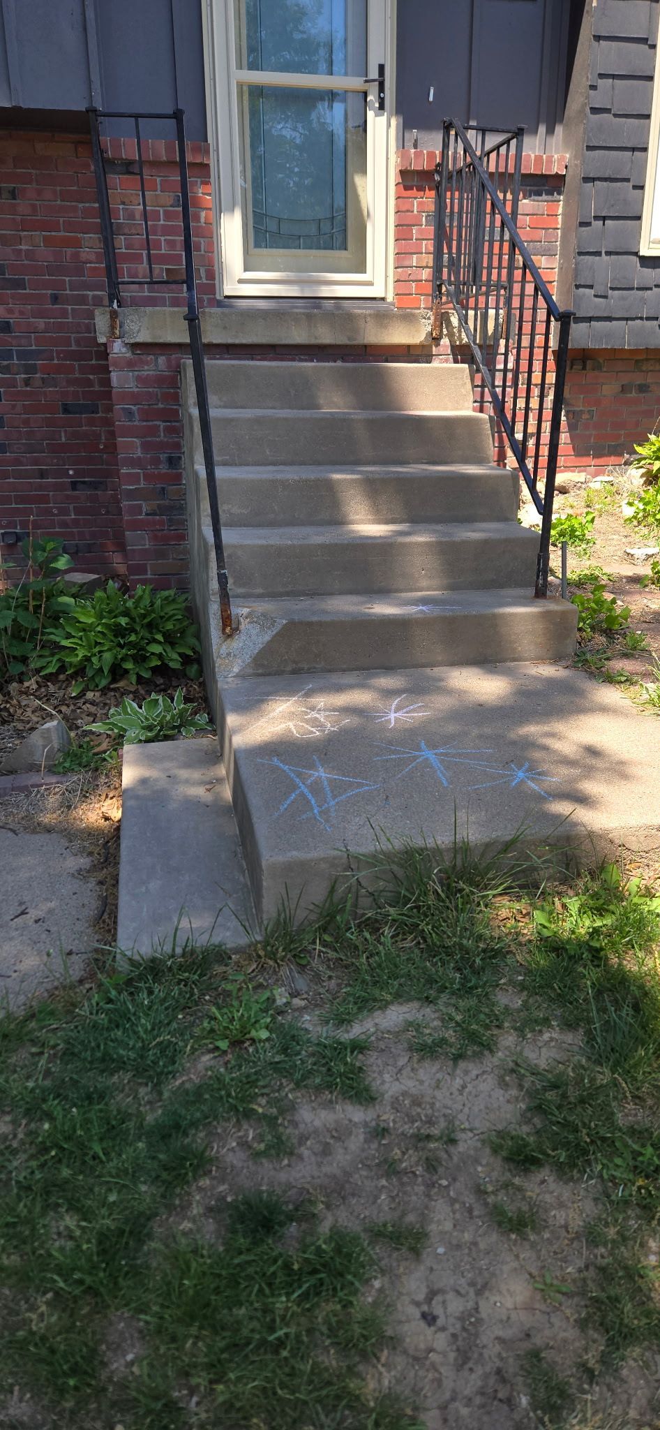 A set of concrete stairs leading up to a brick house.